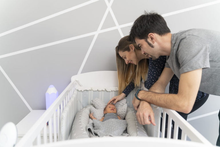 A couple of parents looking their newborn baby in the cradle
