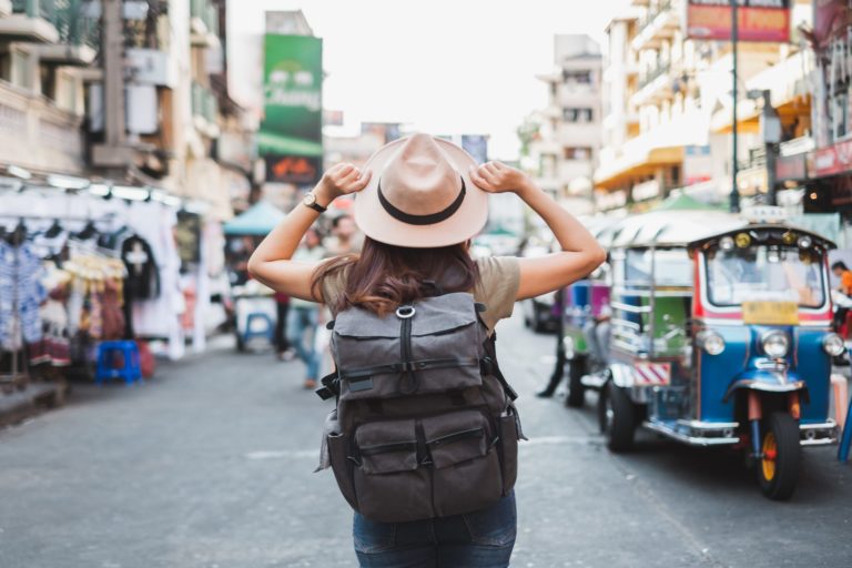 a person with a hat and a backpack walking on a street