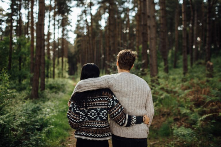 a couple people walking through a forest