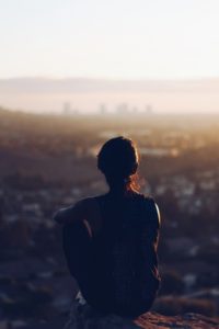 a man sitting on a ledge overlooking a city