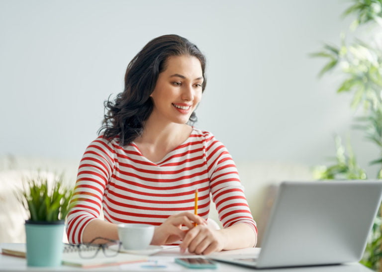 a woman sitting at a table with a laptop and a cup of coffee