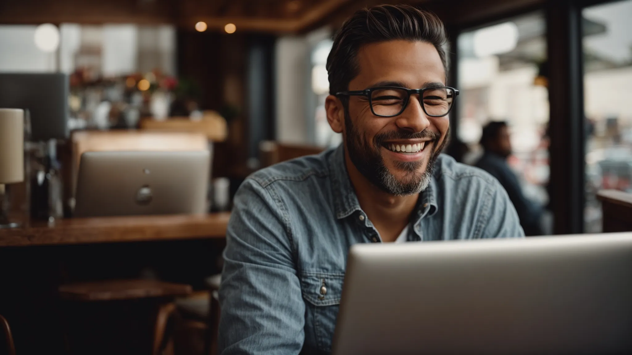 a local business owner smiling while responding to reviews on a computer in a cozy coffee shop setting.