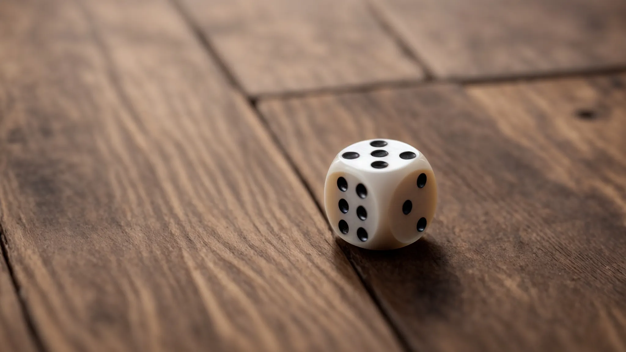 a pair of dice lying next to a coin and a deck of cards on a wooden table.