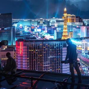 a well-equipped team of roofers works diligently on a vibrant las vegas rooftop, surrounded by the iconic skyline and bright cityscape, showcasing a blend of professionalism and urban energy.