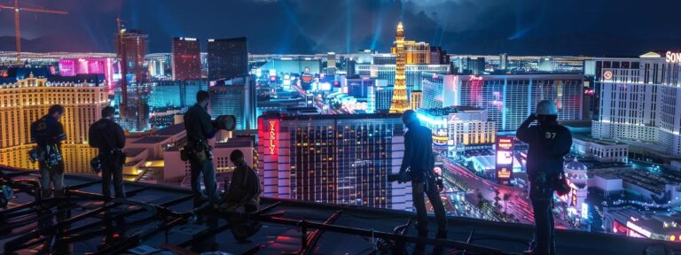 a well-equipped team of roofers works diligently on a vibrant las vegas rooftop, surrounded by the iconic skyline and bright cityscape, showcasing a blend of professionalism and urban energy.