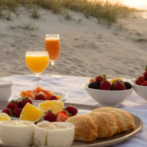 a table set with fresh fruit, pastries, and mimosas overlooks the tranquil myrtle beach shoreline as the morning sun rises.